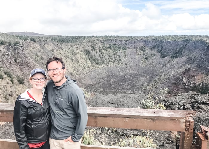 Couple posing with crater in Volcanoes National Park on the Big Island