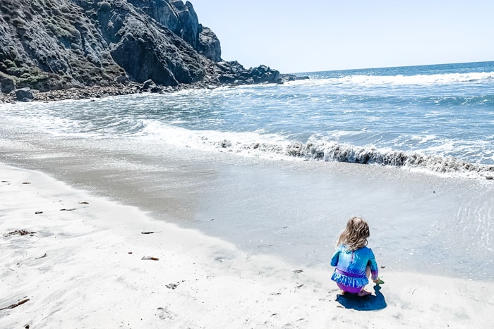 Girl playing in the sand at Pfeiffer Beach (Big Sur, California)