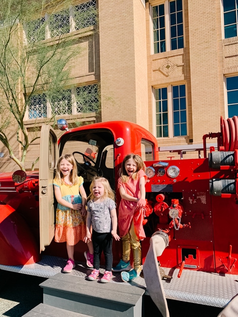 Children posing with a fire truck display at Children's Museum of Phoenix.