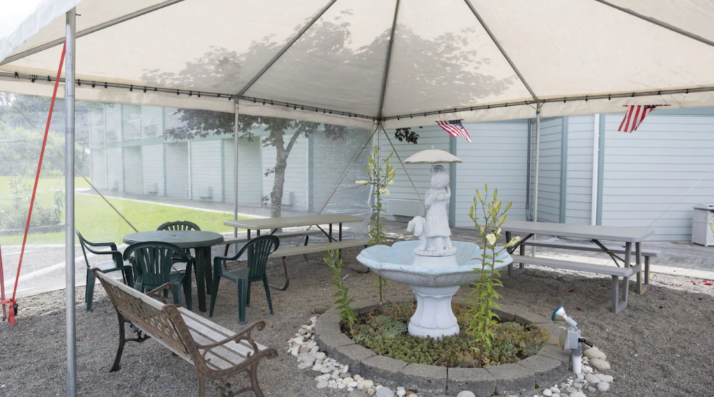 A large umbrella-shaded area with benches and tables at The Dew Drop Inn Motel.