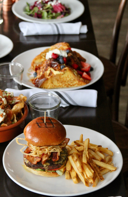Table top at Parrilla Grill, one of the best Boise restaurants, covered in plates of salad, french toast, burgers and fries.