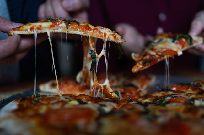 Hands lifting up pieces of pizza from a pan at Luciano's.