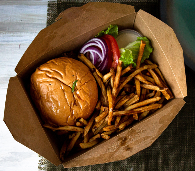 To-go container from Smashburger with a burger, toppings and fries.