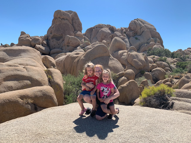 Park visitors crouched on a rock in Joshua Tree in December.