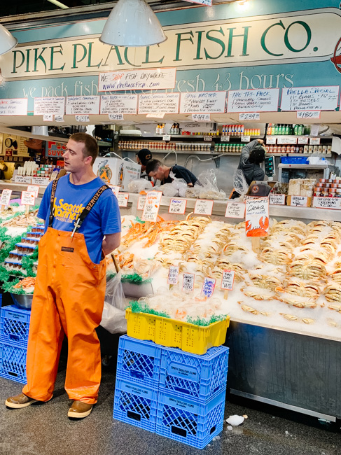 A fishmonger standing in front of a display of seafood at Pike Place Fish Co.