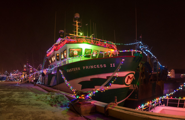 Boat at a dock in Seattle in December, decorated with strings of glowing Christmas lights.