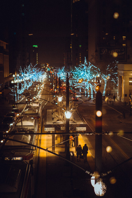 View down a street with trees covered in blue Christmas lights.