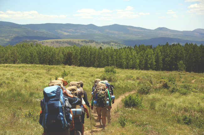 Backpackers walking through a meadow.