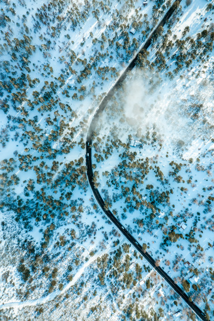 Snowy landscape with a road running through it.